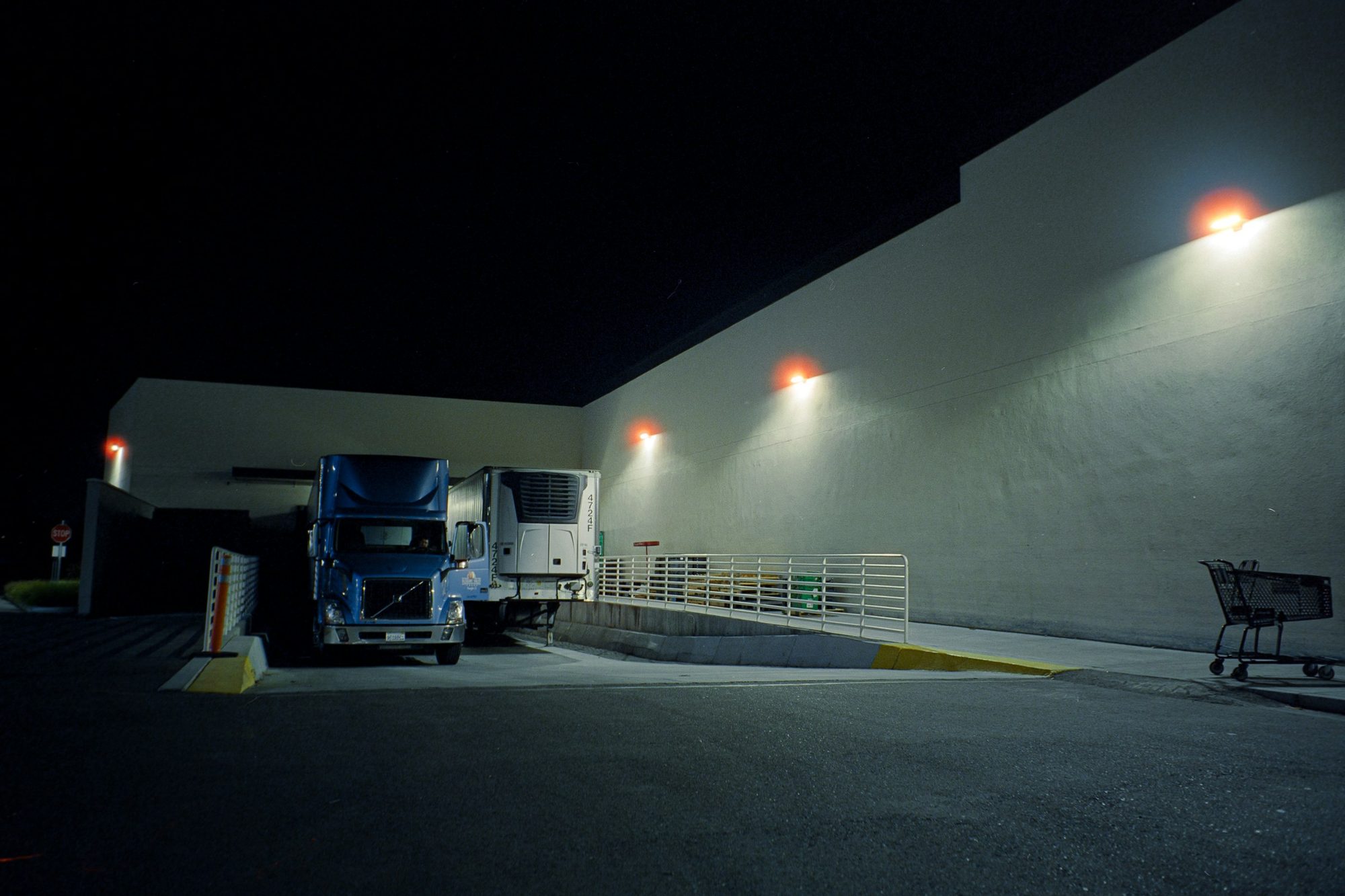 A tractor and trailer backed into a loading dock at night