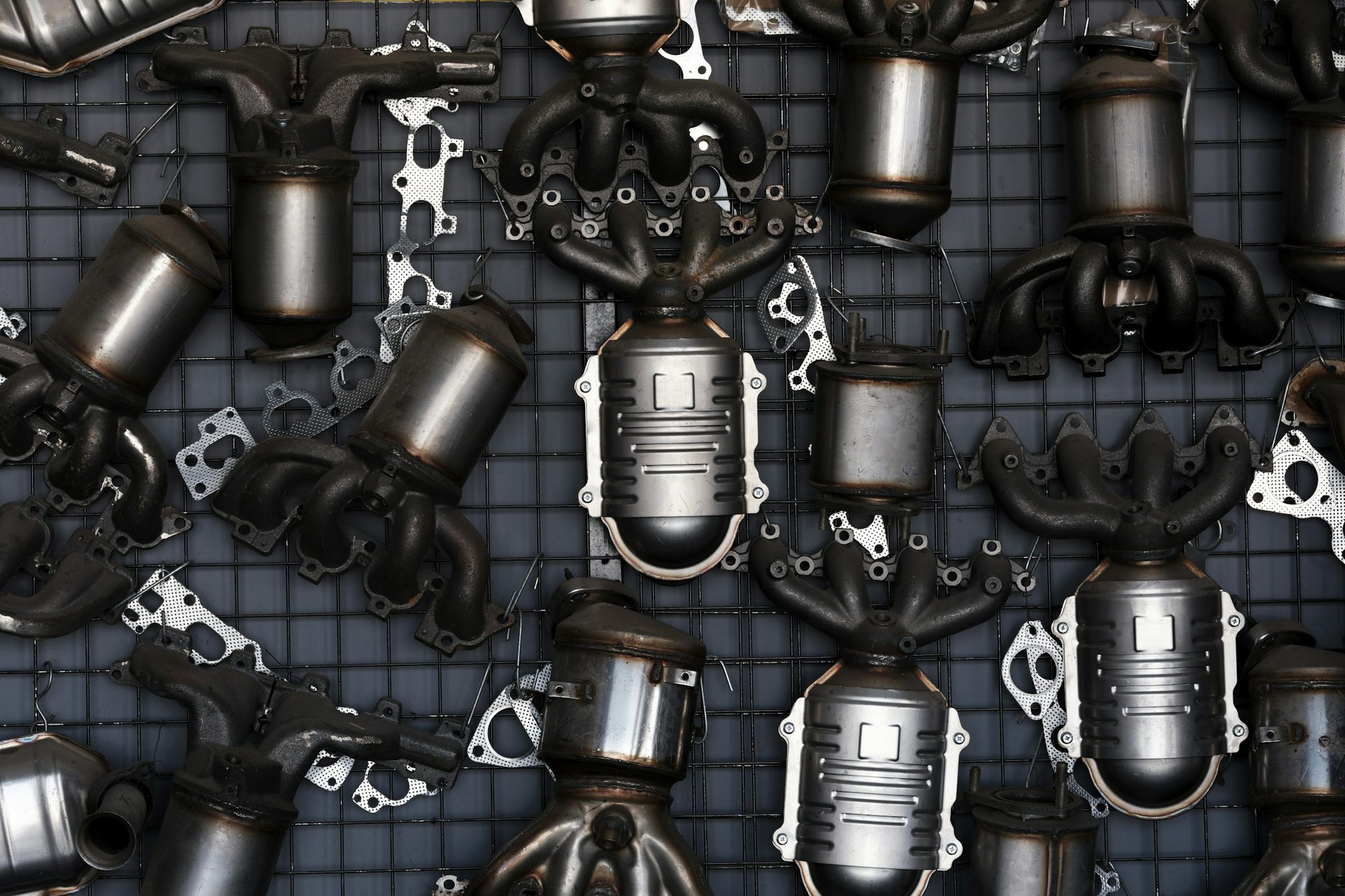 Exhaust manifolds and catalytic converters hung on a parts wall